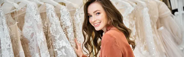 A young bride stands before a selection of wedding dresses, trying to find the perfect gown for her special day. — Stock Photo