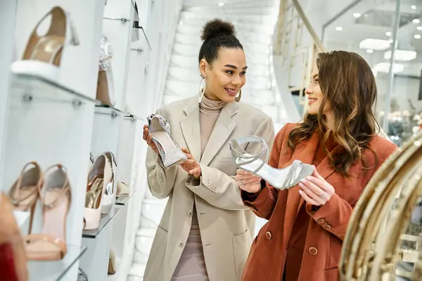 Две женщины, молодая красивая невеста и ее лучшая подруга, изучают варианты обуви в ярком магазине обуви. — стоковое фото