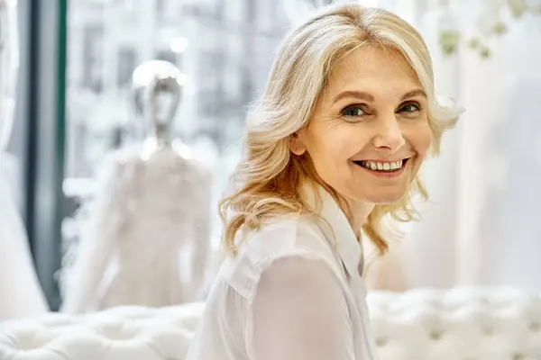 Eine strahlende junge Frau lächelt, als sie vor einer atemberaubenden Ausstellung von Hochzeitskleidern steht.. — Stockfoto