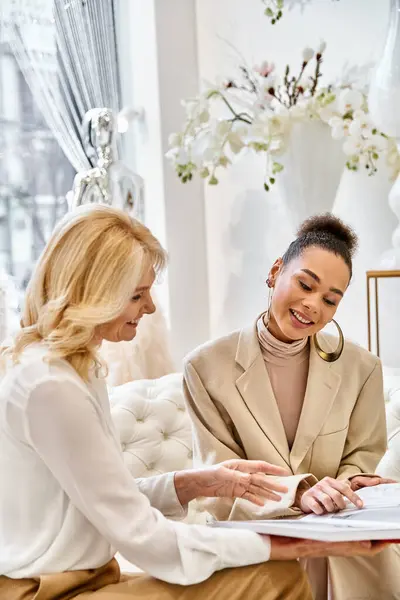 Two sophisticated women engage in a deep conversation while seated on a plush couch in a cozy setting. — Stock Photo