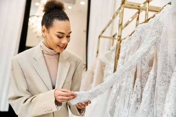 Una giovane bella sposa guarda un abito da sposa su una cremagliera, sorridendo mentre ne guarda uno — Foto stock