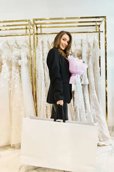 Une jeune mariée brune parcourant un rack de robes dans un salon de mariage. — Photo de stock