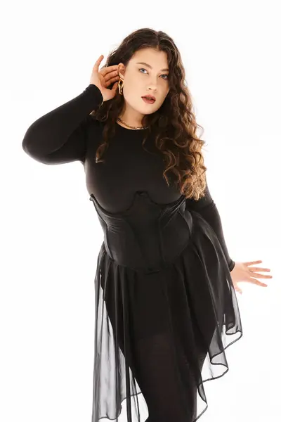 Linda jovem curvilínea em roupa elegante preto com cabelo encaracolado mostrando seu brinco — Fotografia de Stock