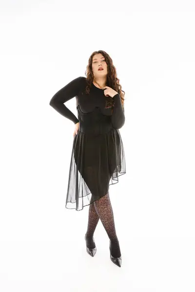 Mulher bonita plus size em roupa elegante preto com cabelo encaracolado posando contra fundo branco — Fotografia de Stock