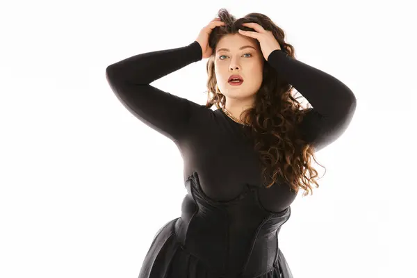 Charming plus size woman in black stylish outfit with curly hair and hand on head posing — Stock Photo