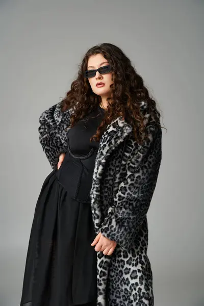 Séduisante fille plus la taille en manteau de fourrure de léopard et lunettes de soleil avec la main à la taille penché vers l'avant — Photo de stock