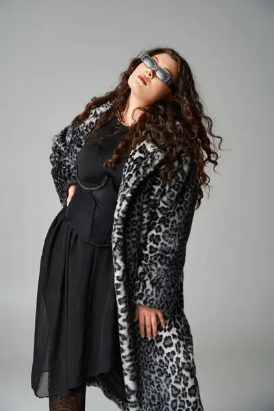 Confident curvy woman in leopard fur coat and sunglasses with hand on waist leaning to forward — Stock Photo