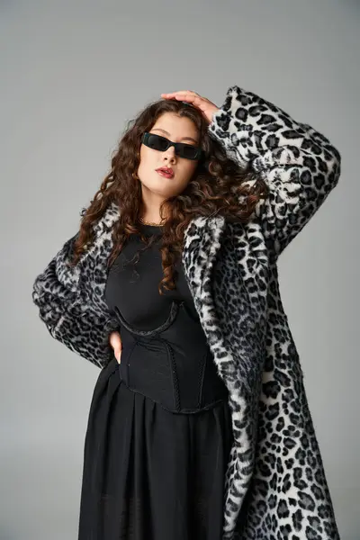 Jolie jeune femme courbée en manteau de fourrure de léopard et lunettes de soleil avec les mains sur la taille et la tête — Photo de stock