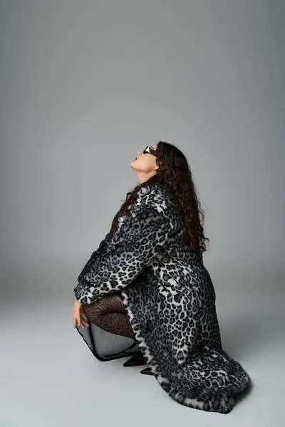 Stylische kurvige Frau in Leopardenfell-Mantel und Sonnenbrille, die seitlich nach oben schaut — Stockfoto