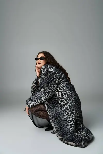 Glamourous curvy woman in fur coat and sunglasses crouching down sideways and looking to camera — Stock Photo