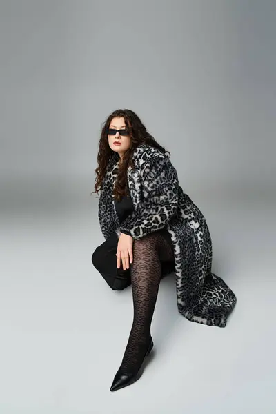 Confident plus size girl in leopard fur coat and sunglasses crouching and putting leg forward — Stock Photo