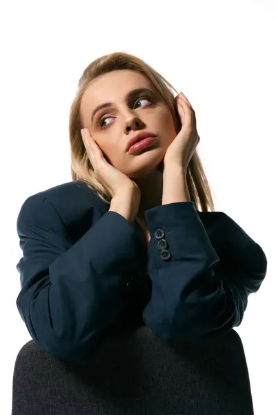 Good looking young woman with blonde hair in elegant blazer sitting on chair and looking away — Stock Photo