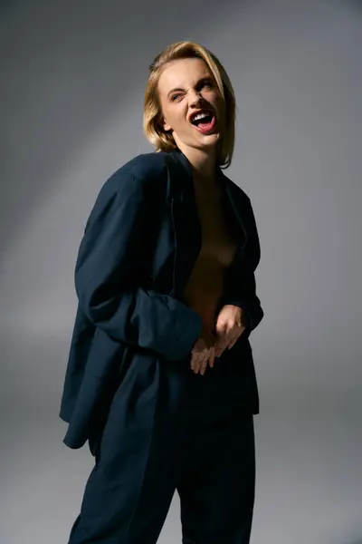 Freudig schöne sexy Frau in blauem Blazer ohne Knöpfe posiert auf grauem Hintergrund und schaut weg — Stockfoto