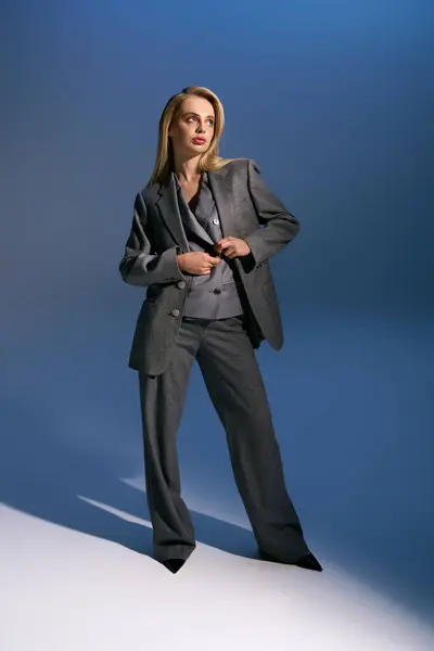 Bela jovem mulher na moda terno de prata posando no fundo azul escuro e olhando para longe — Fotografia de Stock