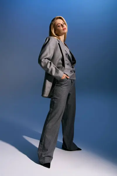 Gut aussehende Frau mit blonden Haaren im schicken silbernen Anzug schaut in die Kamera auf dunkelblauem Hintergrund — Stockfoto