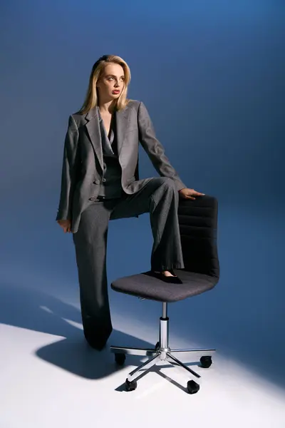 Красива елегантна жінка з світлим волоссям в розумному срібному костюмі, сидячи на стільці і дивлячись геть — стокове фото