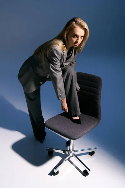 Schöne elegante Frau im modischen silbernen Smoking posiert neben Stuhl und schaut in die Kamera — Stockfoto