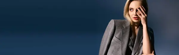 Pretty woman with blonde hair in debonair vest and suit looking away on blue backdrop, banner — Stock Photo
