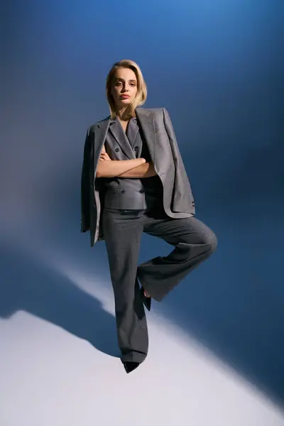 Stylish woman in silver elegant vest and suit posing on dark blue backdrop and looking at camera — Stock Photo