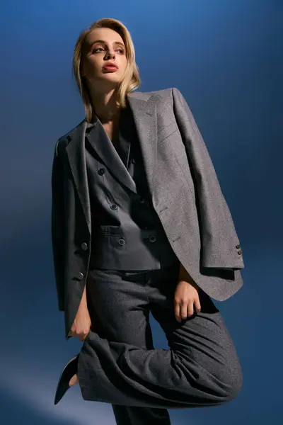 Attractive elegant woman with blonde hair in debonair vest and suit looking away on blue backdrop — Stock Photo