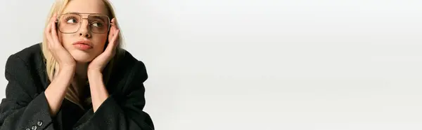 Graceful young woman with blonde hair and chic glasses in black coat posing and looking away, banner — Stock Photo