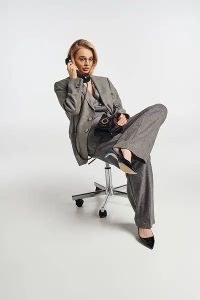 Gut aussehende elegante Frau mit Brille im Debonair-Anzug telefoniert und schaut in die Kamera — Stockfoto