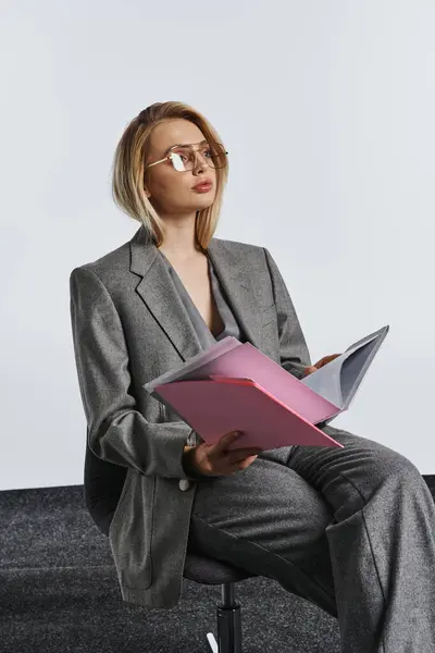 Debonair модный бизнесмен в умно-сером костюме с очками, работающий с ее документами — стоковое фото
