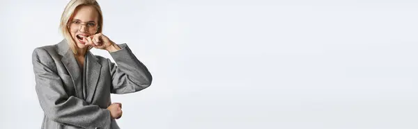 Mulher atraente alegre com cabelo loiro e óculos elegantes em terno cinza olhando para a câmera, banner — Fotografia de Stock