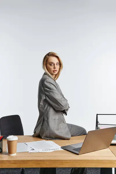 Alluring beautiful businesswoman with glasses in gray debonair suit posing and looking away — Stock Photo