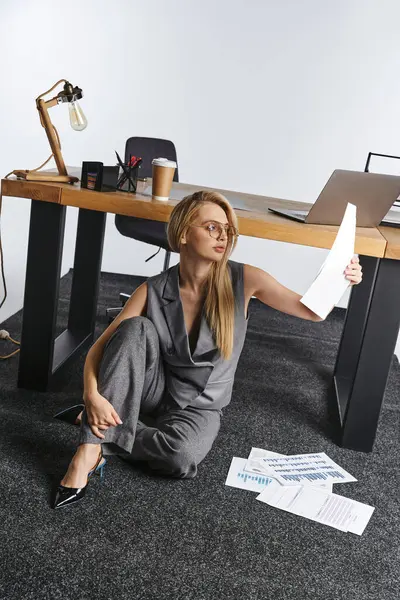 Boa aparência mulher sofisticada em trajes inteligentes trabalhando no chão com papelada e olhando para longe — Fotografia de Stock