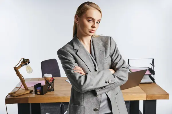Attraktive, hart arbeitende Geschäftsfrau im eleganten grauen Anzug, die vor grauem Hintergrund in die Kamera blickt — Stockfoto