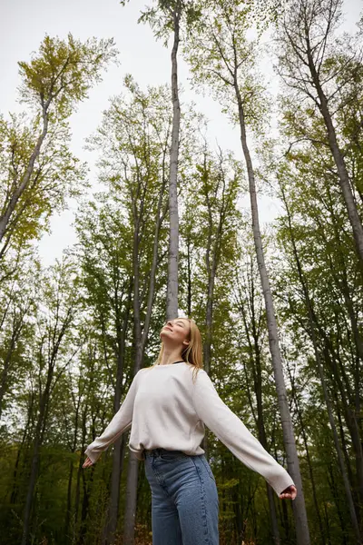 Meditating blonde girl in cozy, sweater hiking in forest and having peaceful moment with closed eyes — Stock Photo
