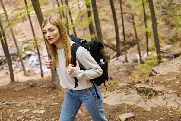 Blonde Naturliebhaberin in Jeans und Pullover, wandert durch den Wald, entdeckt neue Wege — Stockfoto