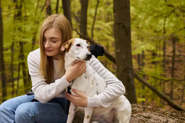 Cena de floresta suave com uma mulher loira exploradora abraçando seu cão, cuidando do conforto de seu animal de estimação — Fotografia de Stock