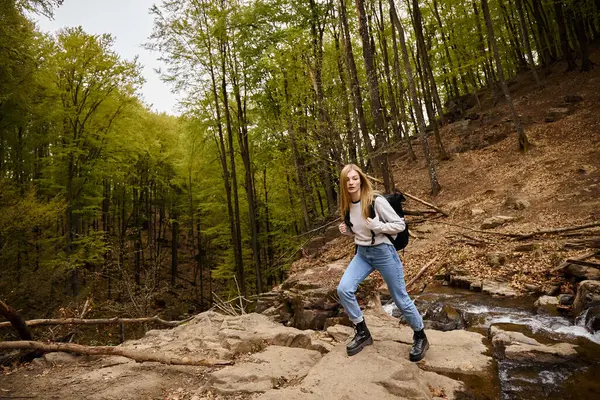 Активна жінка-туристка з рюкзаком, що йде пішки в лісі, пішохідний туризм в осінньому лісі — стокове фото