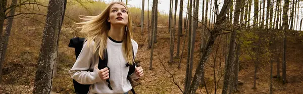 Молода жінка з рюкзаком, що йде в лісі, ходить у похід і ходить у кемпінг на природі, банер — стокове фото