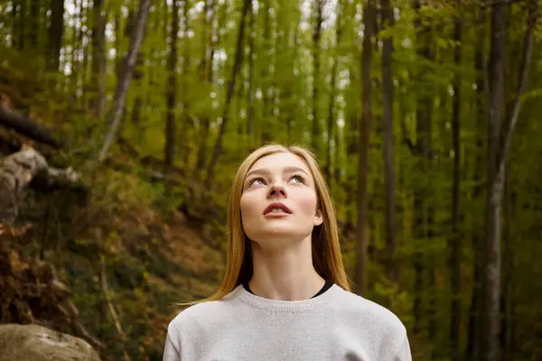 Rilassato donna bionda respirando aria fresca nella foresta in solitario viaggio a piedi guardando nel cielo — Foto stock