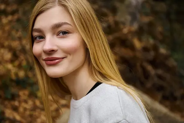 Portrait of smiling beautiful blonde woman looking at the camera while walking in forest — Stock Photo