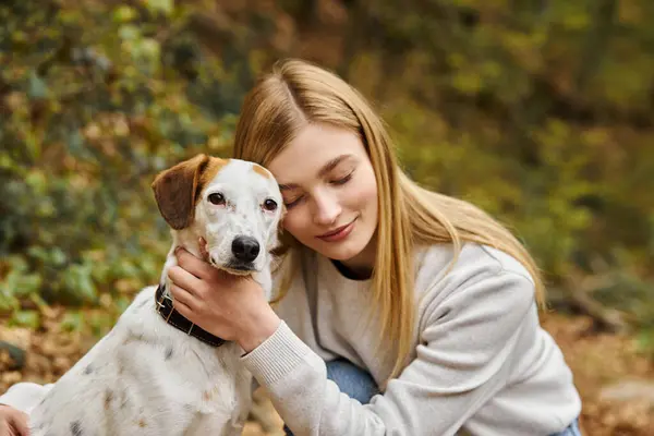 Smiling woman hugging gently her dog companion with eyes closed at forest backpacking trip — Stock Photo