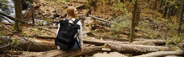 Back view of young blonde female hiker with backpack sitting and resting during trekking, banner — Stock Photo