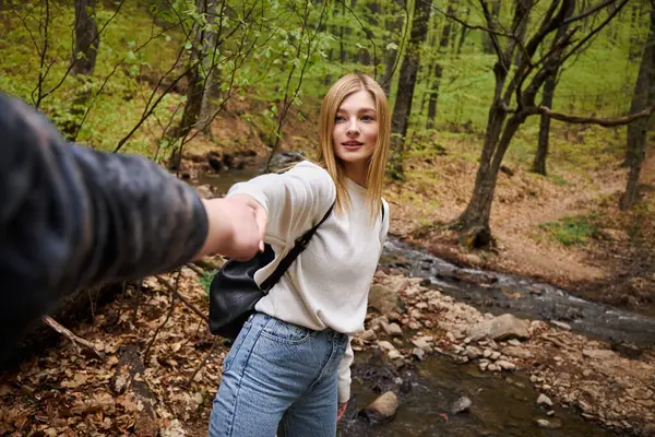 Молодая женщина ведет своего партнера на лесную прогулку, точка зрения снимок пары, держащейся за руки — стоковое фото