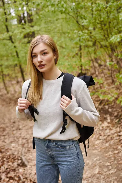 Portrait de jeune voyageuse blonde avec sac à dos randonnée dans la forêt d'automne et debout sur le chemin — Photo de stock