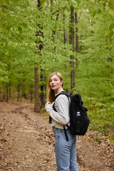 Seitenansicht der blonden hübschen Frau Reisende mit Rucksack auf der Suche nach Richtung zu Fuß im Wald — Stockfoto
