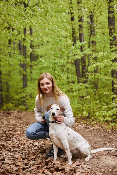Sorrindo menina caminhante interagindo com seu animal de estimação olhando para a câmera enquanto caminhadas resto com vista para a floresta — Fotografia de Stock