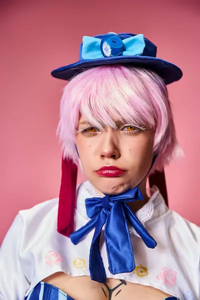 Attraktive junge Cosplayerin mit roten Handschuhen und blauer Mütze posiert emotional auf rosa Hintergrund — Stockfoto