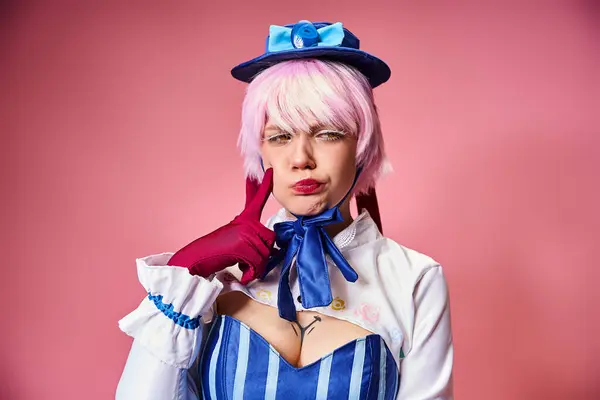 Appealing young female cosplayer with red gloves and blue hat posing emotionally on pink backdrop — Stock Photo