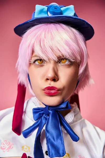 Bello elegante cosplayer femminile con cappello blu in abbigliamento vivace posa attivamente su sfondo rosa — Foto stock