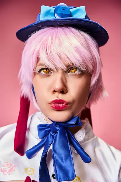 Beautiful stylish female cosplayer with blue hat in vibrant attire posing actively on pink backdrop — Stock Photo