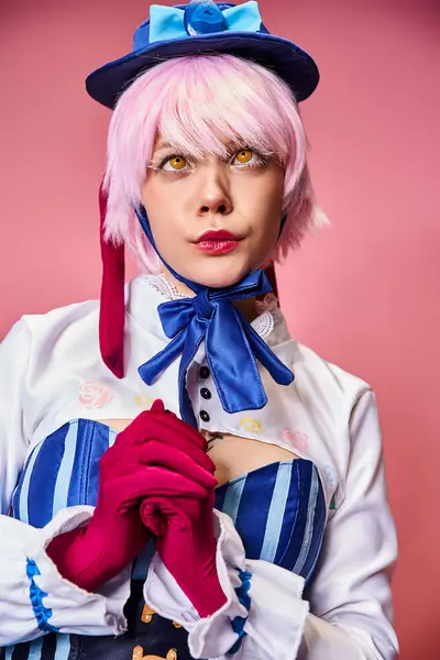 Beautiful stylish female cosplayer with blue hat in vibrant attire posing actively on pink backdrop — Stock Photo