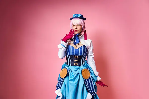 Impactado mujer bonita con sombrero azul y guantes rojos personaje de anime cosplaying y mirando a la cámara - foto de stock